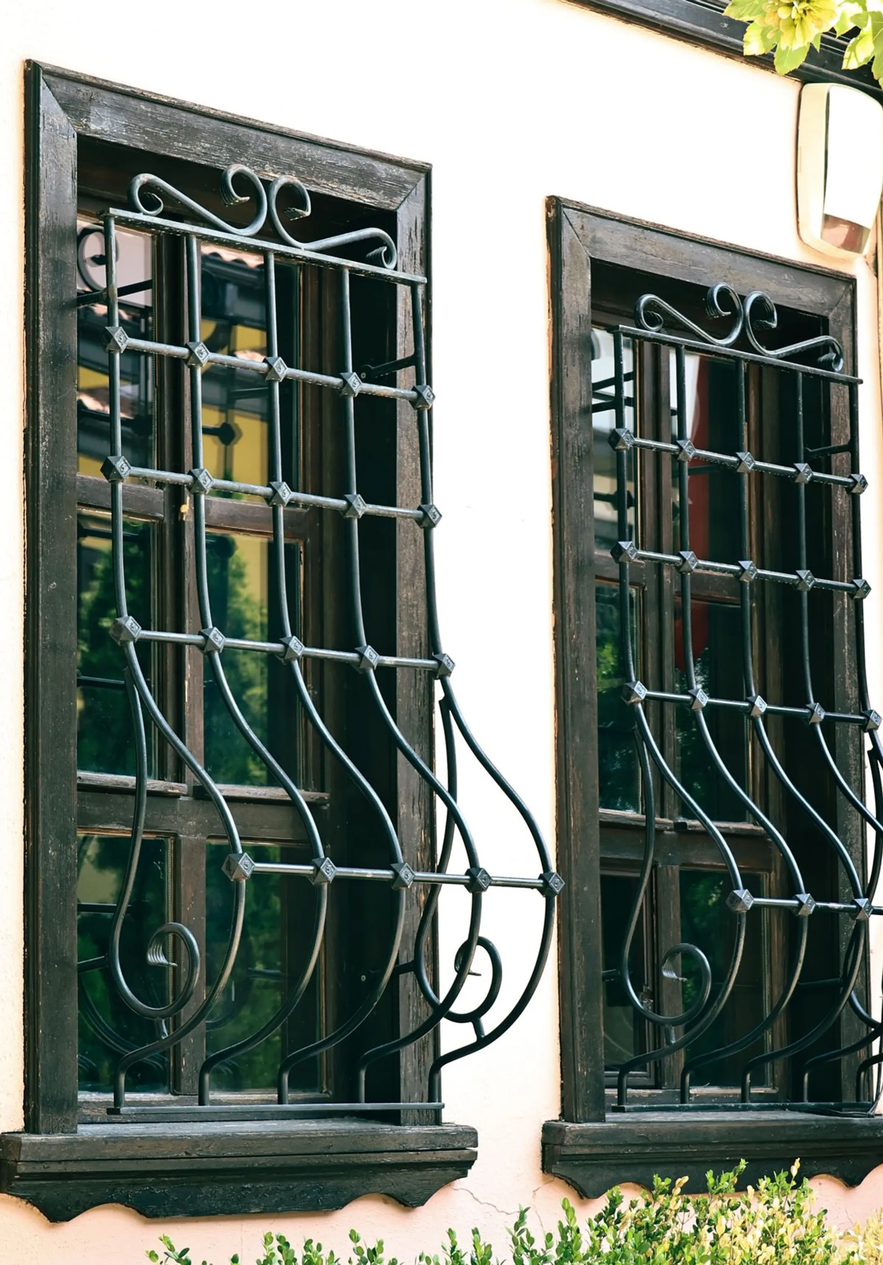 Dark-framed window fitted with a black wrought-iron grille, pale facade